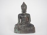 an old bronze statue of a buddha sitting on a rock