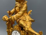 a gold statue of a boy sitting on a clock