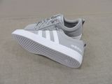 grey and white adidas sneakers with white soles on a beige surface