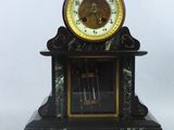 une horloge noire et dorée posée sur un socle en marbre
