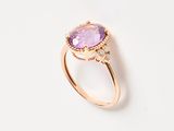 a close up of a ring with a purple stone on a white surface