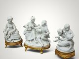 three porcelain figurines of people sitting on a gold stand
