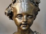 a bronze statue of a young girl with flowers on her head