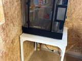 a fish tank sitting on a small table in the corner of a room