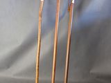 three wooden walking canes sitting next to each other on a gray background