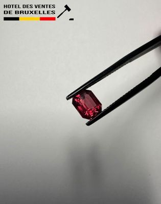 a close up of a pair of tongs holding a red diamond