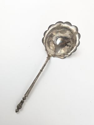 une cuillère en argent ornée d'une fleur sur une surface blanche