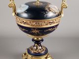 un vase bleu et or posé sur un socle, sur une surface grise