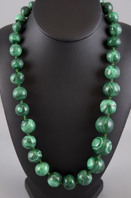 a green beaded necklace on a black mannequin