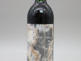une vieille bouteille de vin rouge posée sur une table blanche