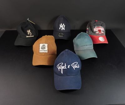 six casquettes de baseball sont alignées sur une surface noire
