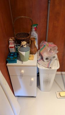 une armoire blanche surmontée d'un panier, à côté des toilettes