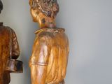 deux statues en bois représentant un homme et une femme debout l'un à côté de l'autre