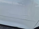 a close up of a white car with a denting on it
