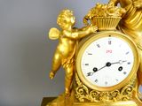 une horloge en or surmontée d'un chérubin et d'un cupidon