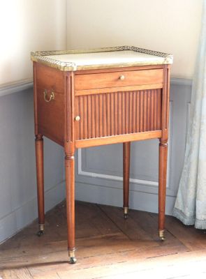 une petite table en bois avec un plateau en marbre, placée dans un coin