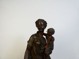 une statue en bronze d'une femme tenant un enfant dans ses bras