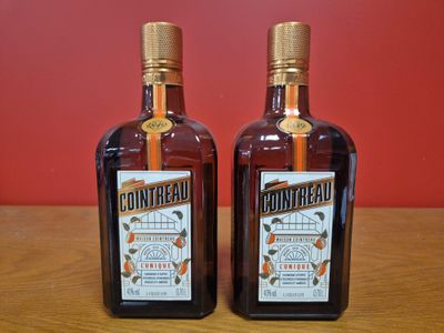 Deux bouteilles de Ginnibreal sont posées sur une table devant un mur rouge.