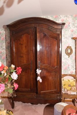 une grande armoire en bois dans une pièce au papier peint à motifs floraux