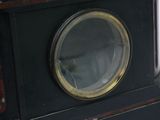 a black clock with a gold rim and a glass window
