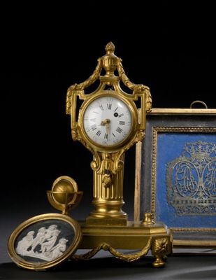 une horloge en or posée à côté d'une photo représentant un homme et une femme