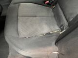 a dirty seat in the back of a car with a broken arm rest