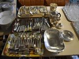 a lot of silverware on a table with a couch in the background
