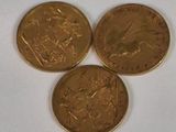 three gold coins sitting on top of each other on a white surface