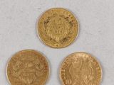 three different types of gold coins sitting on top of a white surface