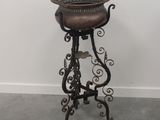 un tabouret ancien en fonte, avec une assise en cuir marron et un piètement en métal