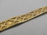 gros plan d'un bracelet en or sur une surface grise