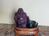 statue d'un Bouddha souriant, assis sur un socle en bois posé sur une surface en marbre