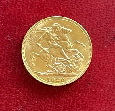 pièce d'or « sovereign » posée sur un tissu rouge, sur fond rouge