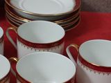 six cups and a saucer on a red table cloth