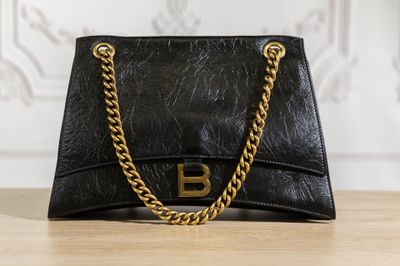 un sac à main noir muni d'une chaîne dorée, posé sur une table en bois