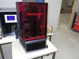 une grande imprimante 3D rouge posée sur une table blanche