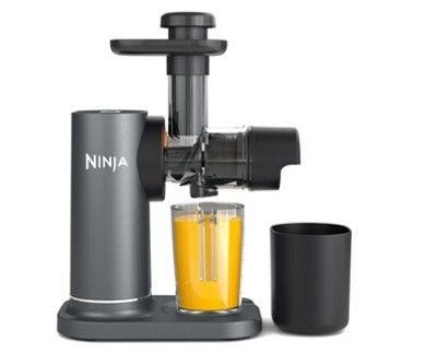 un gros plan d'un extracteur de jus avec un verre de jus à côté