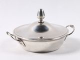 une casserole en argent avec un couvercle, posée sur une surface blanche