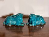 two blue ceramic animals sitting on a wooden table