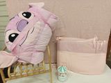 une peluche rose posée sur une chaise à côté d'un lit de bébé