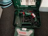 une boîte à outils verte posée par terre, contenant des outils