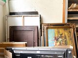 a television sitting on top of a table next to a pile of framed pictures
