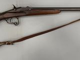 un vieux fusil accroché au mur à côté d'une paire de chaussures