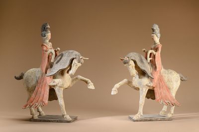 two figurines of a woman riding a horse and a man riding a horse