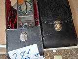 a black case with a multimeter in it next to a black case with a note