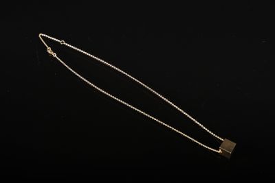 un collier en or avec un pendentif de forme carrée au bout d'une chaîne