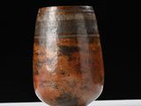 un vase marron posé sur une table blanche