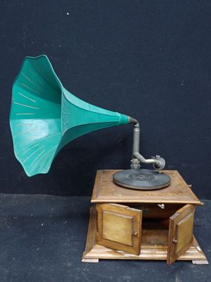 un gramophone vert posé sur une table en bois près d'un mur noir