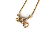 a close up of a gold necklace with a snake on it
