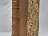 an old book sitting on top of a white table next to a white wall